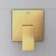 Goldene Brausearmatur mit quadratischer Grundfläche und einem kantigen Hebel, montiert an einer hellen Wand. Ideal Standard-Logo auf der Oberfläche sichtbar.